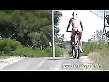 Naked Babe Cycles Through Countryside