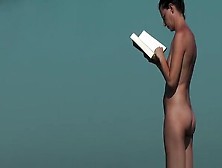 Nudist Woman Reading Book In The Beach