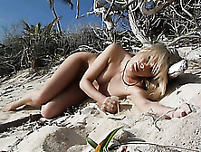 Blonde Sensually Touches Self While Lying Naked On Sandy Beach.